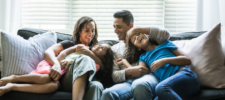 Family sitting on the couch laughing.