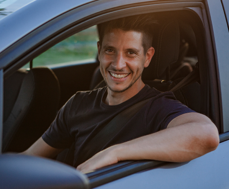 Young man smiles on board his car